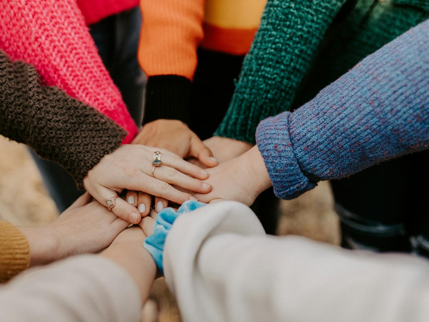 A group of people joining hands in the middle of a circle